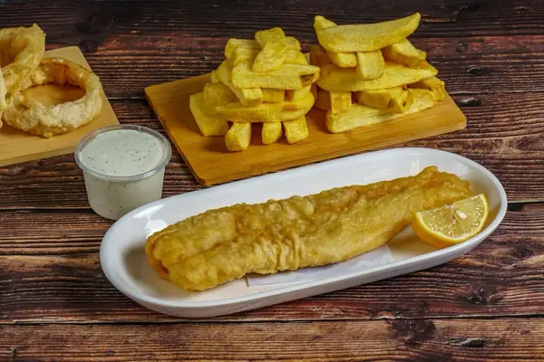 Battered fish with a lemon wedge and a stack of chips