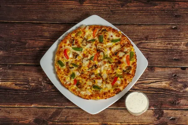 A veggie garden pizza with peppers, sweetcorn and mushroom on a white plate